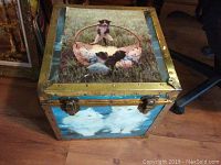 Front-top corner view showing the kitten basket image on the hinged lid and the brass metal corners, rivets, and latches.