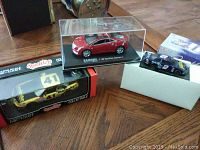 Photo shows all three die cast cars including the Cadillac and two NASCAR cars, with visible packaging and cases.