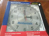 Front view of Mastercraft circular saw blade clock in original box, showing entire clock face, packaging details, and product branding.