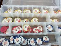 Top-down view of plastic compartment box with yellow, red, and blue hockey coins showing player portraits.