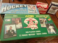 Four boxes of sports cards featuring a 1991-92 O-Pee-Chee Hockey box, 1991 Score Baseball Collector Set, and two other unopened boxes placed together.