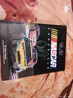 Front cover of NASCAR Chronicle book signed by Dale Earnhardt Jr featuring race cars and the signature visible on the cover.