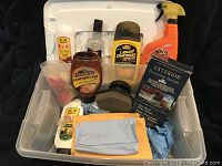 Photo showing all car cleaning products including Armor All, Simoniz, and Turtle Wax brands, and cleaning tools in a white storage container.