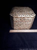 Closed handcrafted square wooden enamel box showing intricate inlaid pattern in cream, green, gold, and maroon colors alongside a ruler for size reference