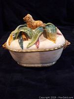 Front view of the casserole dish with the lid on, showing the lion figure and decorative leaves on the top.