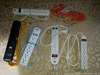 Six electrical power cords including power strips and extension cables with switches and multiple outlets.