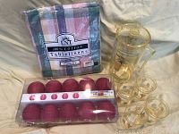 Full lot showing plastic pitcher, four plastic glasses, cotton tablecloth packaged, and packaged red paper lantern string lights.