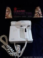 White Andis Hang Up ProTurbo 1600 hair dryer alongside the ceramic styling tool with original packaging featuring hair styles.