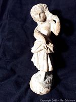 Front view showing the woman standing with a dress and basket, with visible weathering and glaze loss.