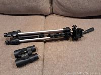 Vivitar tripod folded with black plastic mount and handle, metal legs visible, on carpet.