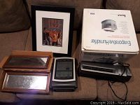 Overview photo showing humidifier box, tower fan, weather station, framed print, and two small mirrors on a couch.