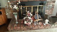 Full view of items arranged on fireplace hearth including florals, fireplace tools, log holder, basket, bells, and figurine