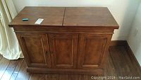 Closed wood grain veneer dry bar buffet showing front panel doors and hinged top closed.