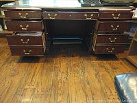 Front view of wooden executive desk showing open drawer and surface detail