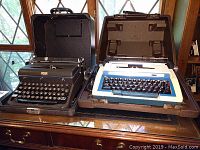 Photo showing both typewriters side by side on a wooden surface with cases open