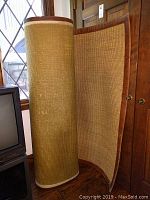 Rolled and standing view of the woven sisal rug with leather edging.