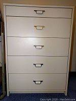 Front view of white dresser showing closed drawers and metal handles.