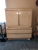 Front view of closed vintage armoire, showing two large lower drawers and two cabinet doors above.