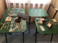 Four vintage folding tray tables with black metal frames and green tops shown with assorted jewelry on tops