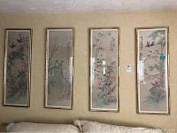 Four framed Asian prints arranged horizontally on a wall. Each features birds, floral branches, and calligraphy. Bamboo-style frames in gold tone. Prints show vintage styling with color tones of green, blue, red.