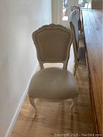 Single ornate dining chair showing carved wooden frame and cream upholstery on seat and backrest.