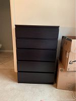 Full front view of tall dark wood dresser with 5 drawers, showing clean lines and sleek modern design.