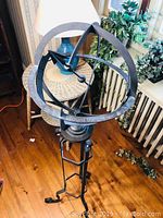 Overhead angled photo showing entire gyroscope-style ornamental sundial with part of the stand and surrounding environment.