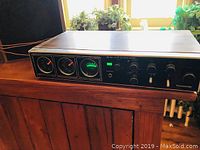 Front angled view of the Panasonic stereo receiver showing analog meters, knobs and wood grain finish.