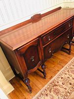 Full side angle view of the antique Craftsman buffet showing wood finish, ornate drawer and cabinet fronts, turned legs, and stamped drawer inside.