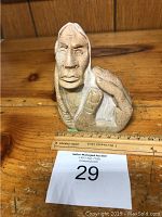 Front view of Inuit sculpture showing detailed facial features and hand position.