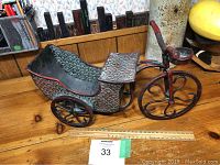 Side angle view of metal rickshaw bike cart showing details of painted designs and structure.