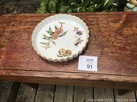Top view of 10 inch white porcelain plate with peach and flower design, scalloped edges and gold trim