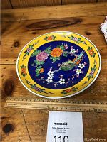 Full view of one hand painted plate showing complete floral and bird motif with ruler for size reference approximately 9.5 inches.