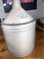 Front view of a vintage cream-colored stoneware jug with a blue crown and number 2 mark, with double blue horizontal lines for decoration.