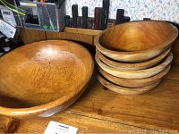 Large wooden salad bowl and six smaller bowls stacked, showing natural wood grain and finish.