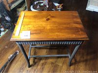 Front view of wicker table with finished wood top showing wood grain and wicker skirt under the top.