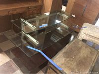 Glass tiered media table with three glass surfaces and dark wood base, lived-in environment