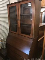 Front and side view of the vintage wooden secretary desk, showing drop-front writing surface and glass cabinet doors.