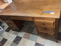 Front angle view of vintage wood desk showing six drawers and surface wear.