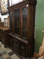 Front and side view of the vintage wooden china cabinet showing glass doors, wood finish, and carved accents.