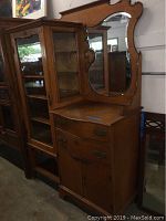 Front and angled side view showing the full vintage oak cabinet with glass door and shaped mirror.