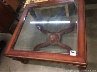 Top view of glass top coffee table showing carved wooden frame and glass inset