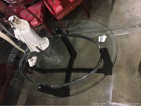 Top view of oval glass coffee table with ceramic angelic statue and small bird figurine on top