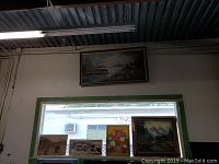 Wide view showing six framed pieces of wall art displayed above and near a window. Artwork depicts nature themes including landscapes and flowers.