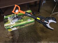 Worx Jawsaw electric pruning shear resting on boxed traveling sprinkler