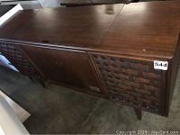 Front angled view of the wooden Zenith console stereo showing the wood veneer finish, woven lattice speaker covers on each end, and central cabinet doors.