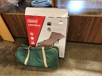 Packaged Coleman Converta camping cot box with tan cot folded alongside in a carrying bag with beige straps