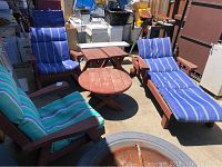 Overview of several pieces of redwood patio furniture with cushions, including rocking chair, wheeled chairs, tables, and benches.