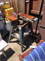 Full view of Kraft metal table sander unit showing rust and four-legged frame with motor below, sanding belt and drum visible.