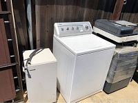 Kenmore 800 electric top load washing machine and Toshiba wheeled cabinet with white surfaces and black handle, shown outside against a wooden fence.